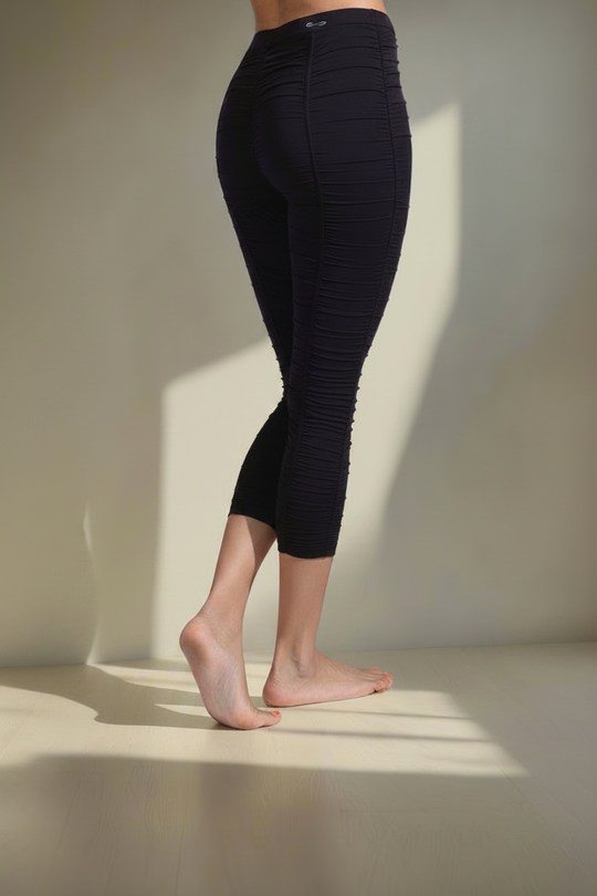 Person wearing black leggings standing against a neutral background
