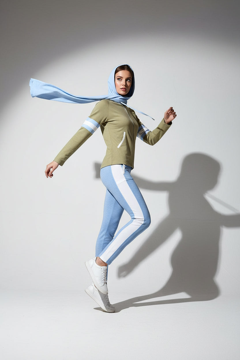 Woman wearing a green top and light blue pants with a matching scarf on a white background
