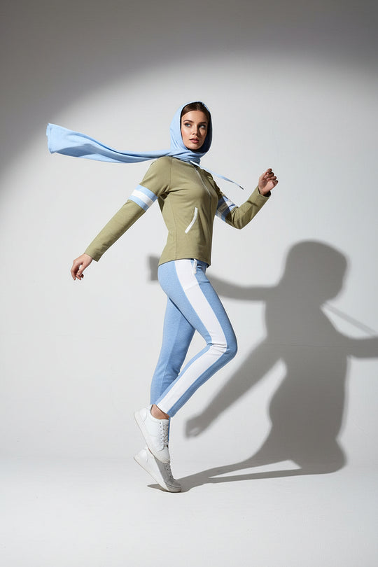 Woman wearing a green top and light blue pants with a matching scarf on a white background